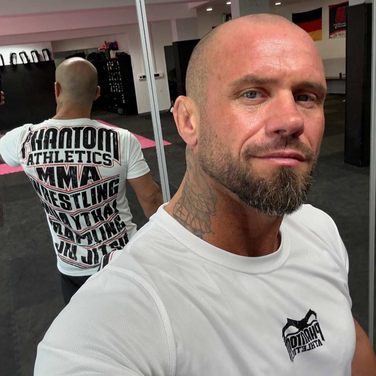 Das weiße EVO MMA Sports Training Shirt kombiniert modernes Design mit Funktionalität und eignet sich ideal für Kampfsport und Fitness. Es ist atmungsaktiv und hält Sportler selbst bei intensiven Workouts kühl und trocken. MMA Fighter Sebastian Risch mit dem MMA Sports Shirt.
