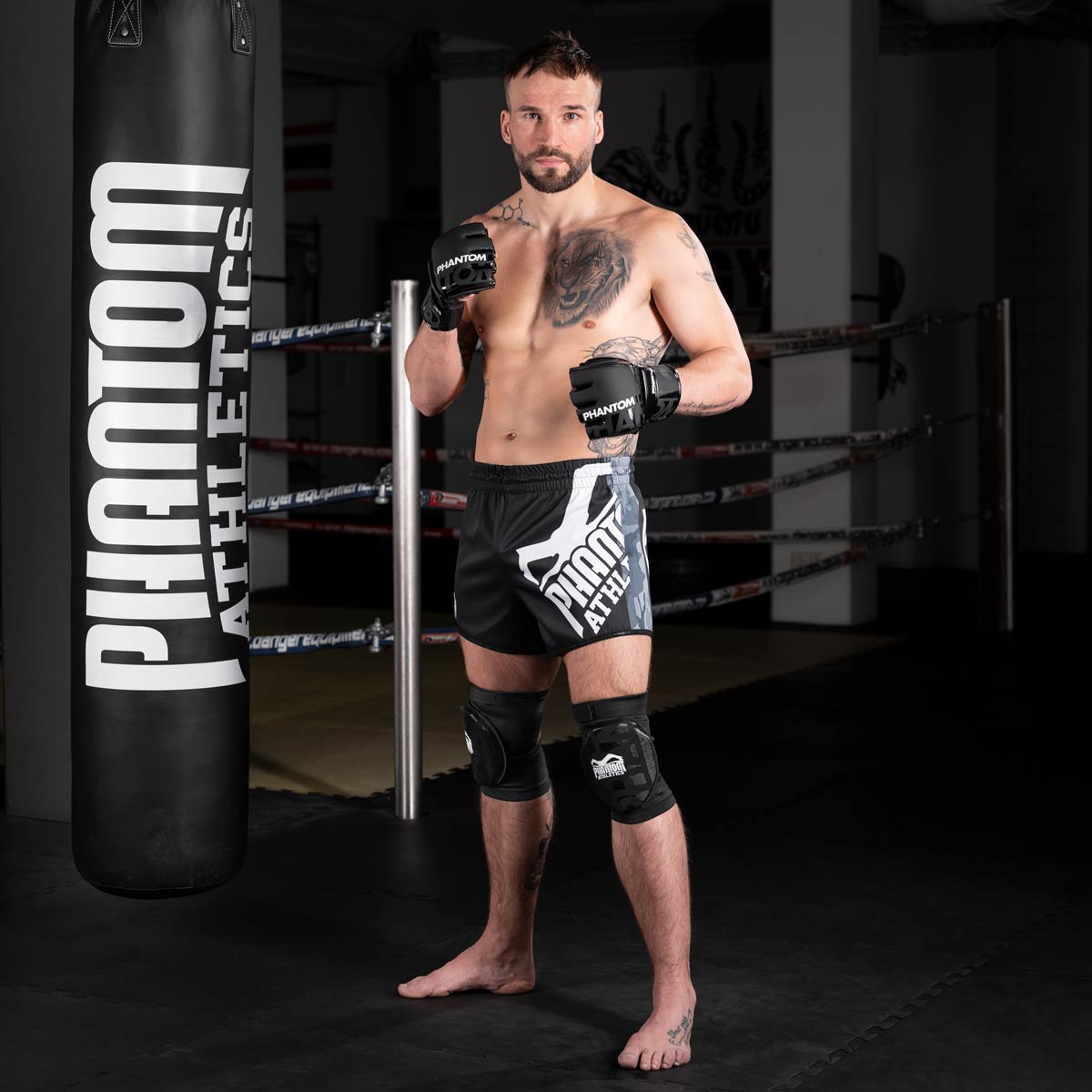 Kampfsport Profi im Gym beim Training mit dem Phantom High Performance Boxsack, der Phantom Fightshorts, Phantom Apex Knieschonern und den Phantom MMA Hybrid Apex Handschuhen