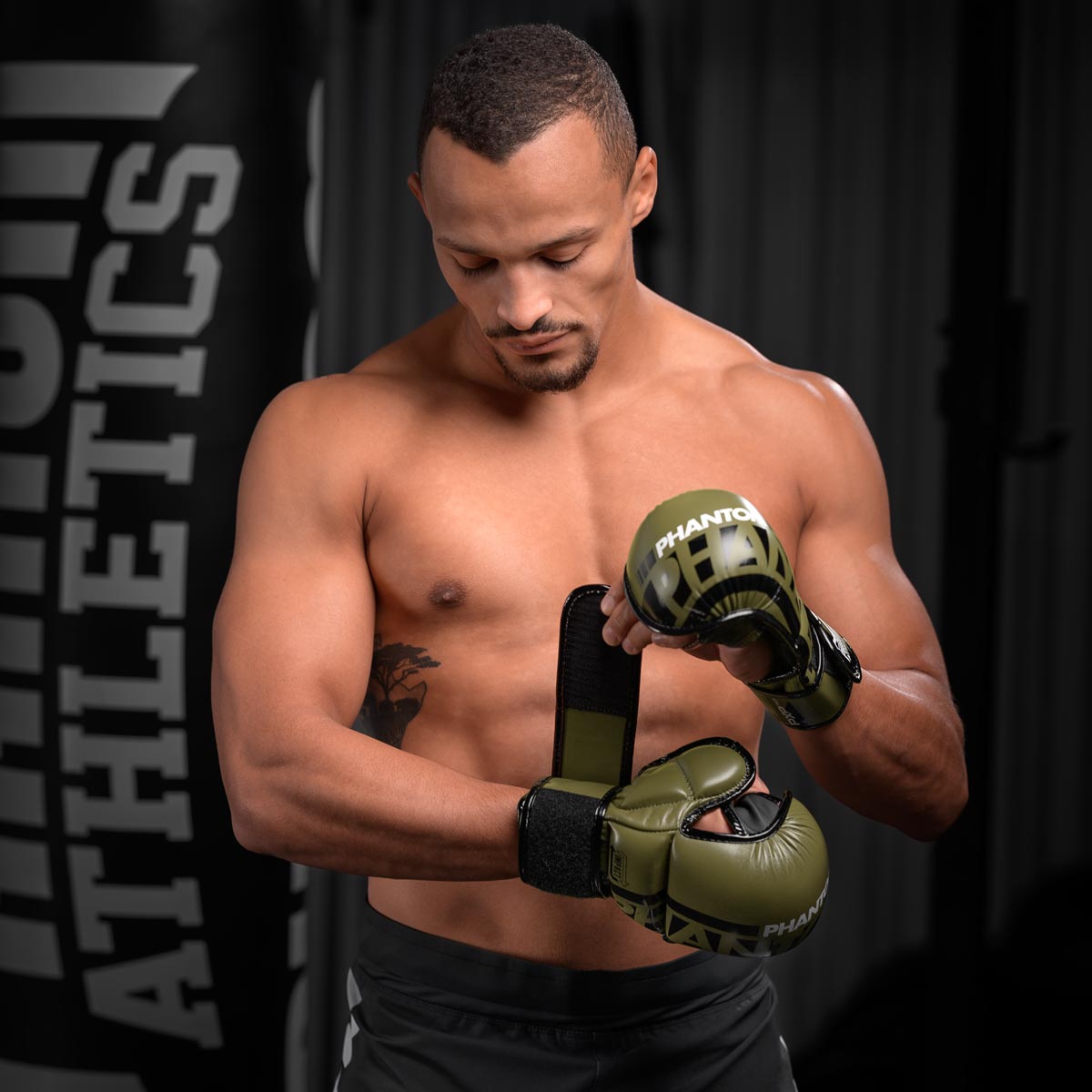 Karan Mosebach schließt die Phantom Apex MMA Sparringhandschuhe in Army Grün und macht sich fertig für sein Boxsack Training